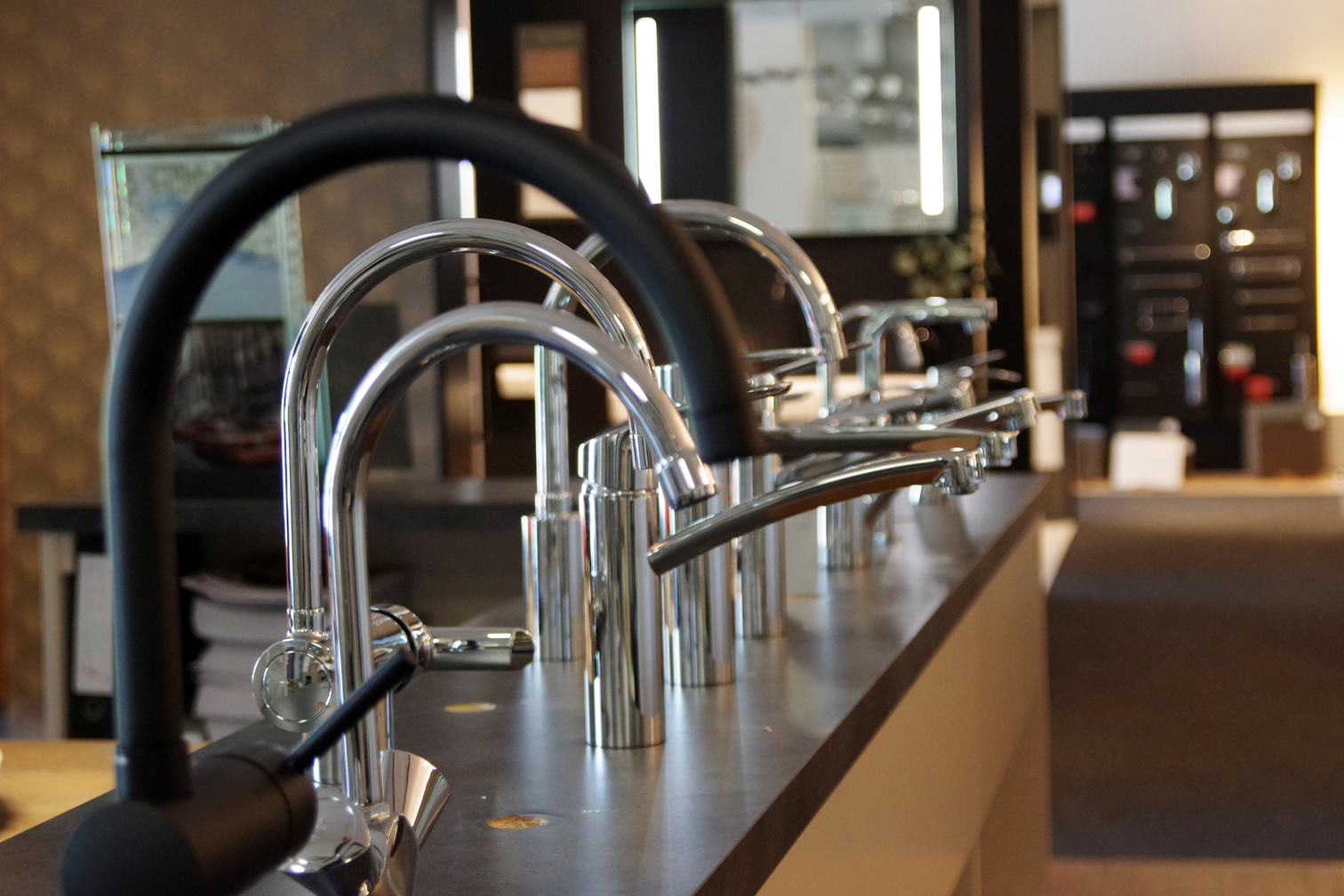 Showroom met moderne keuken- en badkamerkranen in diverse stijlen, waaronder matzwart en chroom, gepresenteerd op een donker werkblad