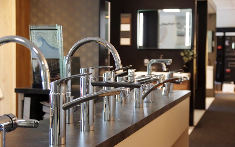 IMGP0332 Showroomopstelling met diverse moderne chromen keuken- en badkamerkranen gepresenteerd op een donker werkblad
