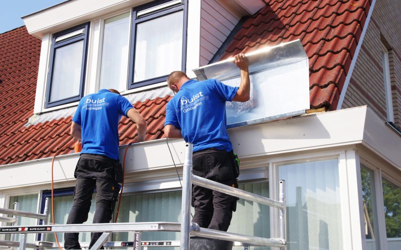 IMGP0338 Installateurs van PBuist uit Grootegast aan het werk op een steiger bij een woning met rood pannendak, tijdens montage van dakbedekking of zinken boeiboord